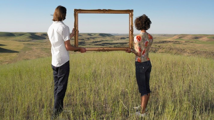 man and woman holding frame in open land